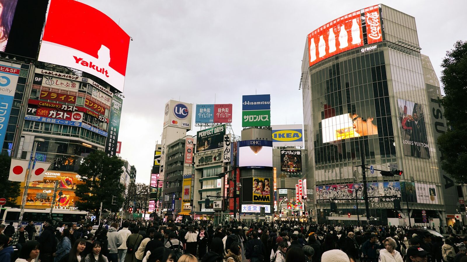 a crowd of people walking down a street next to tall buildings