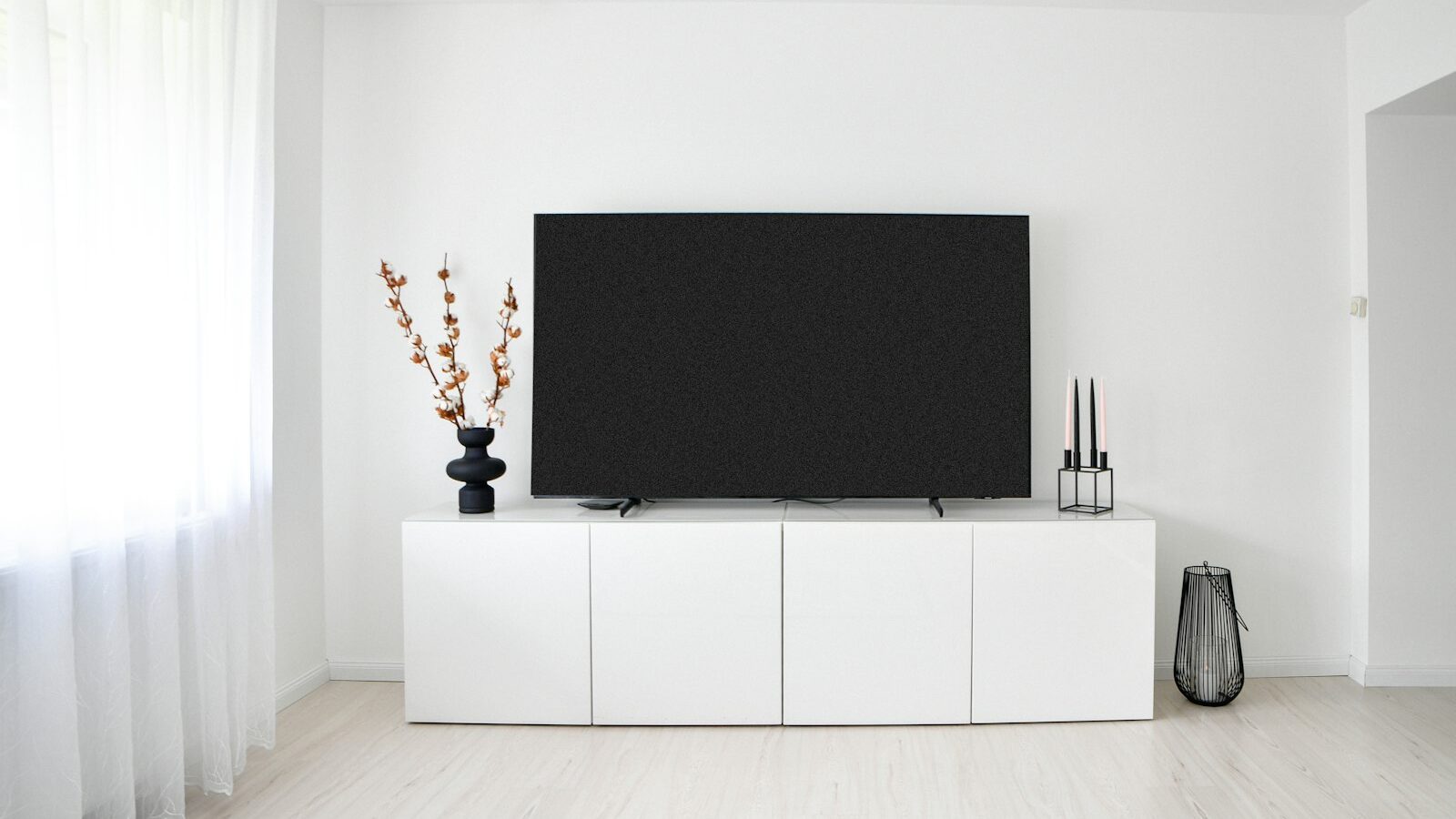 White minimalist room with television and storage cabinet.