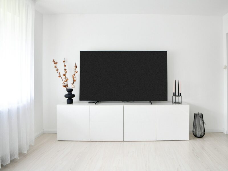 White minimalist room with television and storage cabinet.