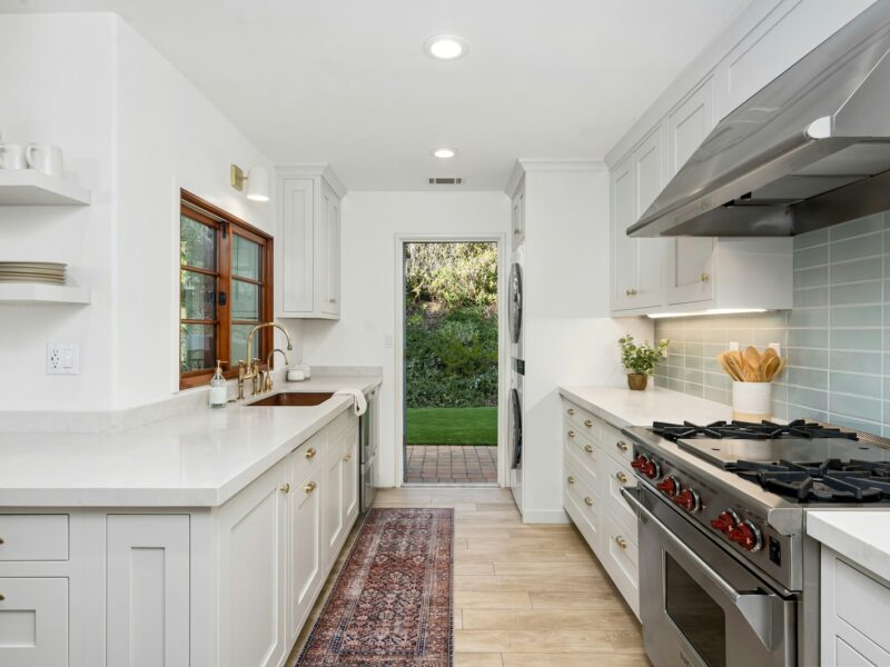 A kitchen with white cabinets and a stove top oven