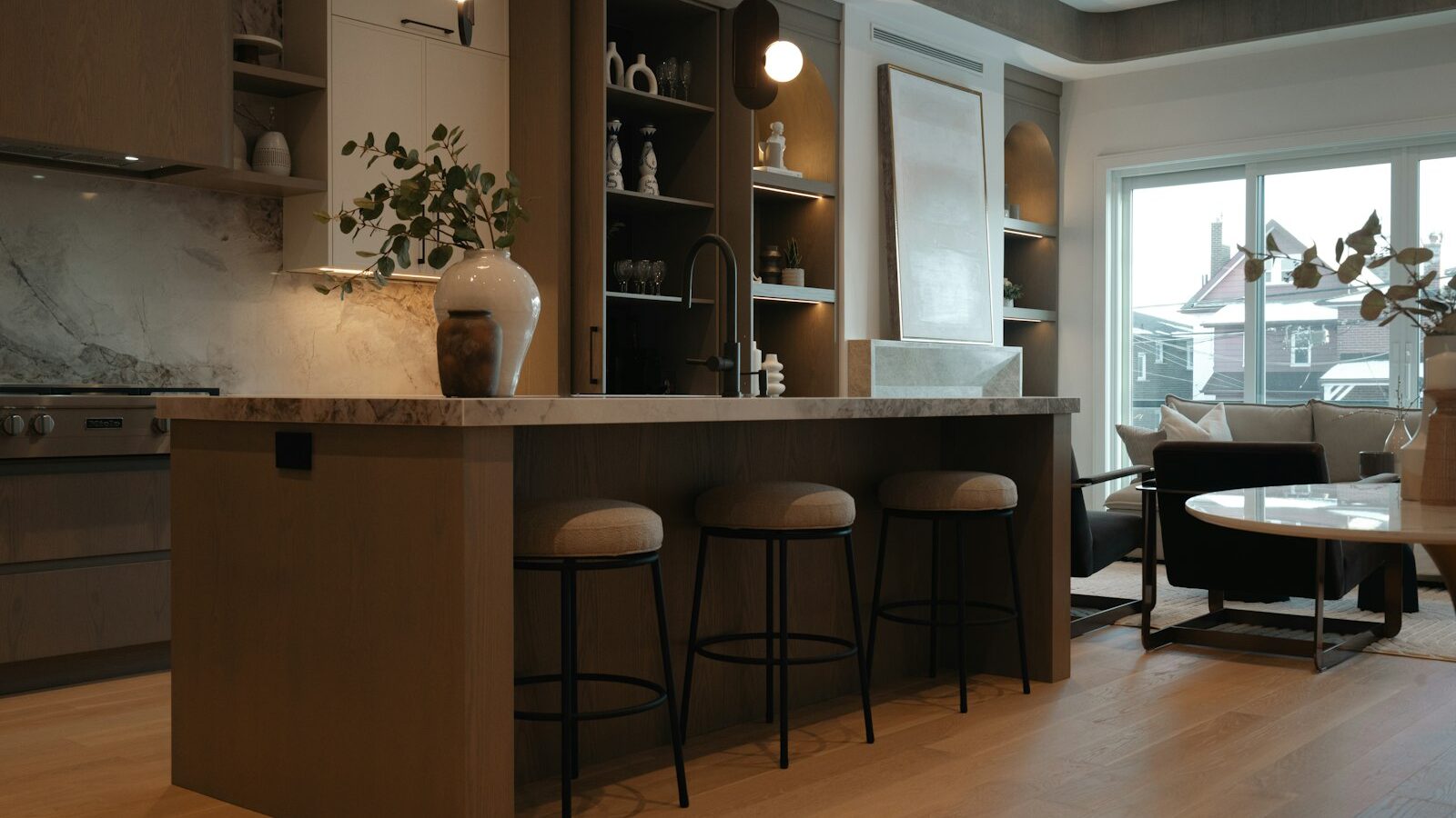 Modern kitchen island with stools and living area view.