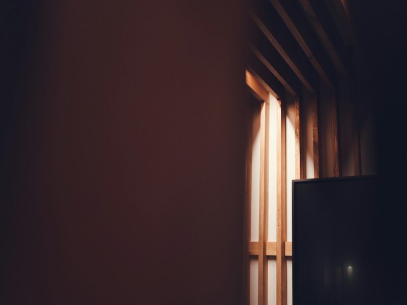 Narrow light beam entering a dark room with wooden slats.